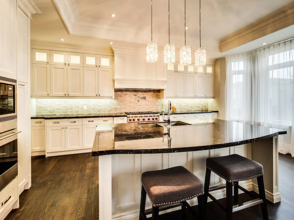 Bright kitchen with white cabinetry, a dark island countertop, and wood flooring from the Great 6 portfolio
