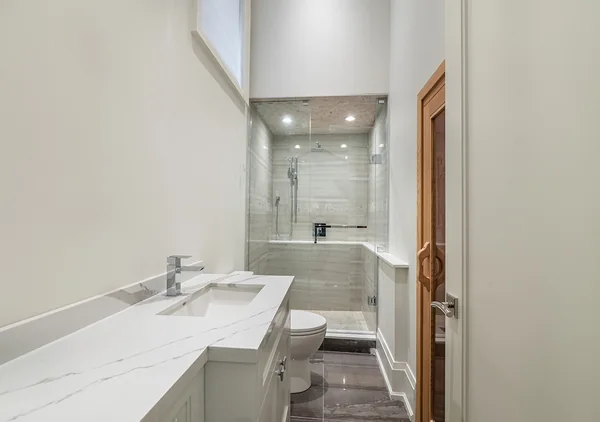 Bevdale Road: Narrow bathroom with double vanity and shower at the far end