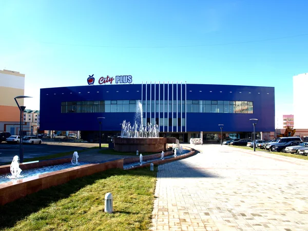 City Plus: Blue shopping-centre facade with fountain and paved approach