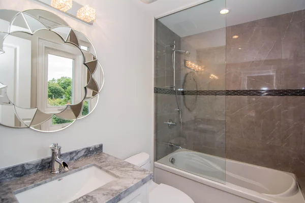 Joicey Boulevard: Bathroom vanity beside a tiled bathtub and glass screen