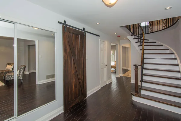 Tilman Circle: Curved staircase beside a sliding wood door and mirrored cupboard