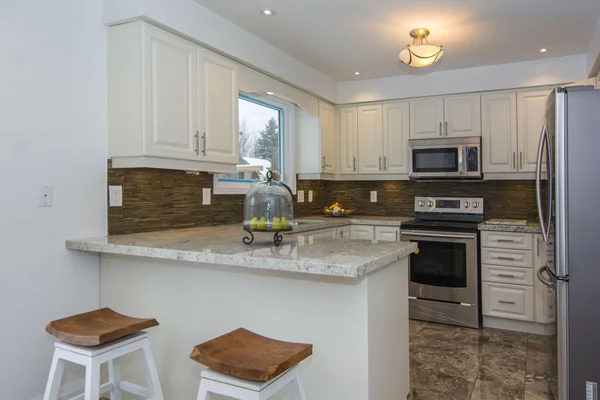 Tilman Circle: White kitchen with breakfast counter and stainless-steel appliances