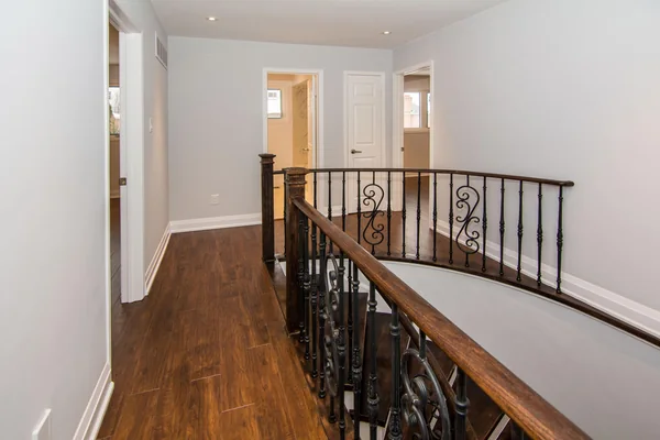 Tilman Circle: Upper landing with wood handrail and metal balusters