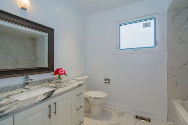Tilman Circle: Bathroom vanity and mirror beside a high window