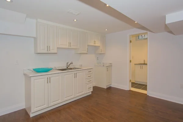 Tilman Circle: Lower-level kitchenette with white cabinets and wood-effect flooring