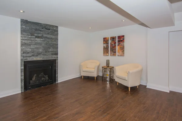 Tilman Circle: Lower-level living room with stone fireplace and two chairs