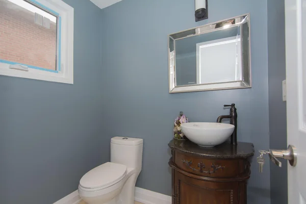 Tilman Circle: Powder room with blue walls and basin on a wood cabinet